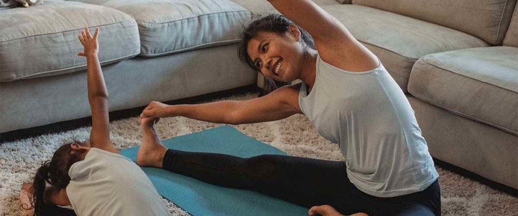 Mom Exercising with her Kid on a Yoga Mat with Big Smile