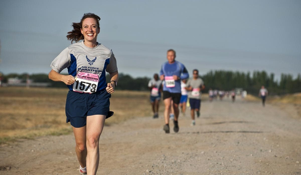 Woman running in the front during a race with a smile. 