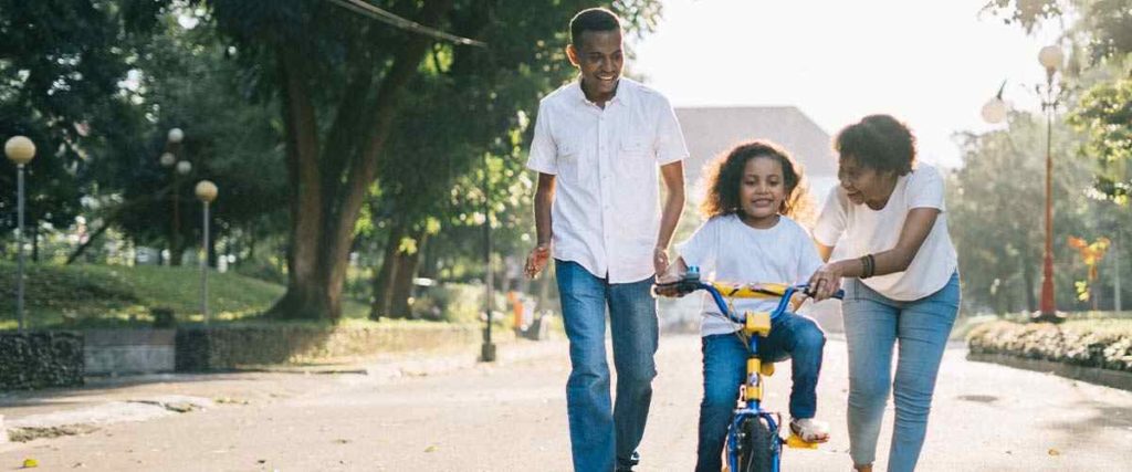 family teaching their child to ride a bike