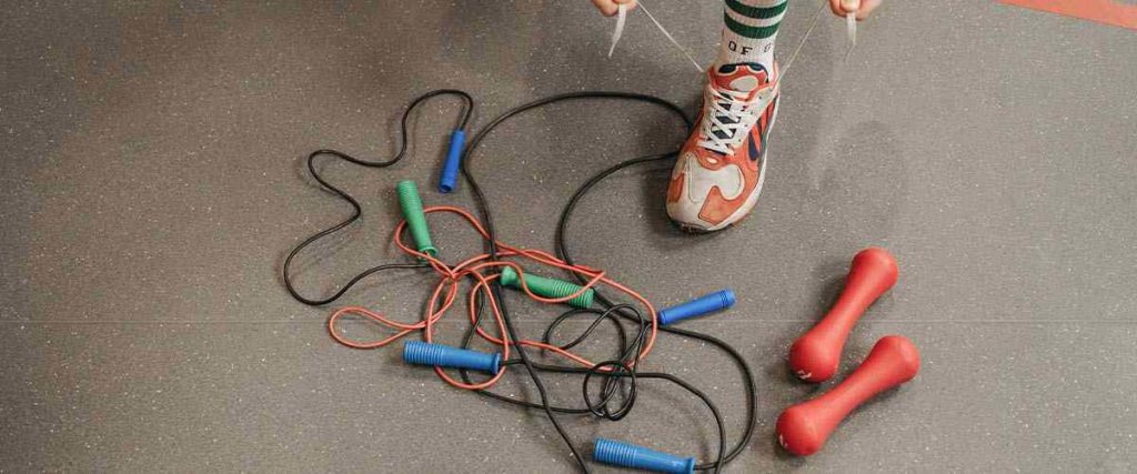 Man Tying his Shoes Next to Two Jump Ropes