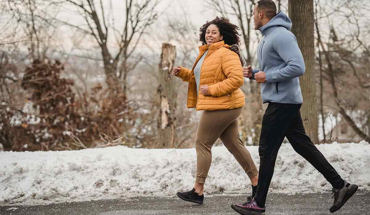 A couple running in the winter smiling at each other.