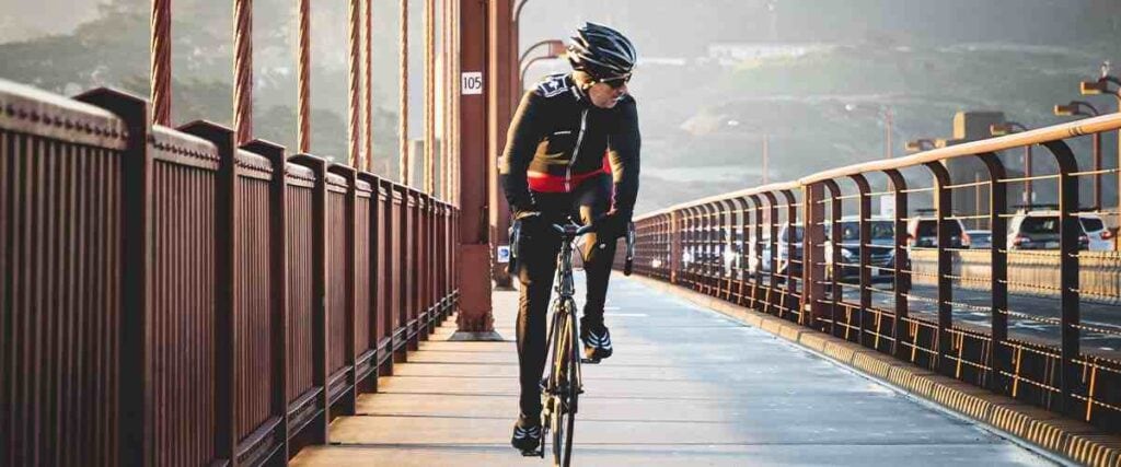 Man cycling on city bridge next to highway