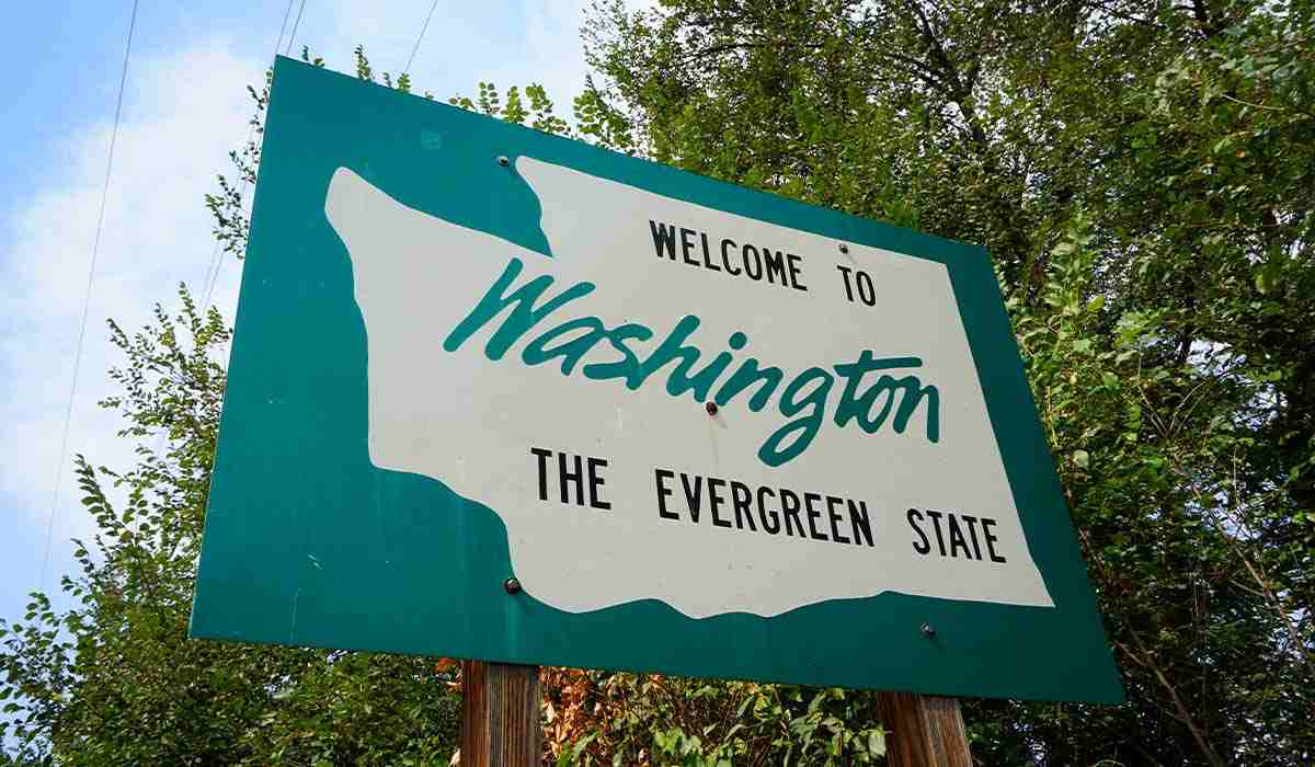 Welcome sign on the side of the road when entering Washington State with the words "Welcome to Washington. The Evergreen State."