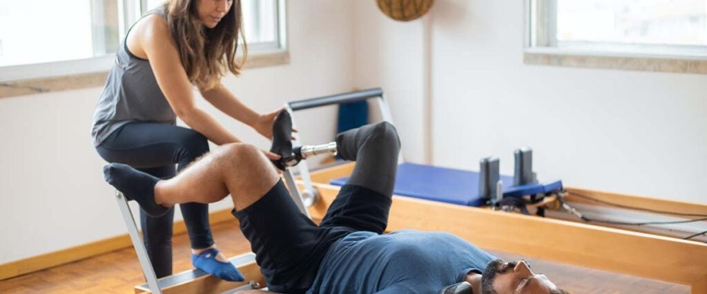 A Man Doing a Pilates Exercise with Personal Trainer.