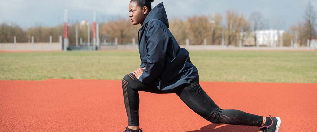 Woman doing lunges on school track field. 