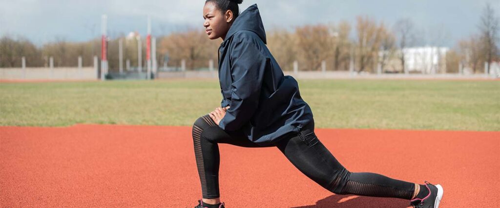 Woman doing lunges on school track field.