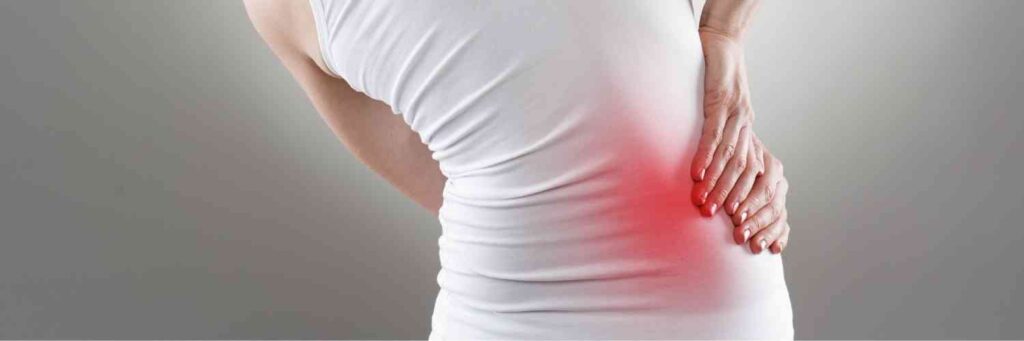 A woman holding her hip in pain with a red area where it hurts the most. 