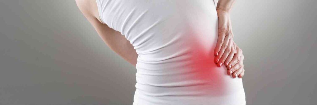 A woman holding her hip in pain with a red area where it hurts the most.
