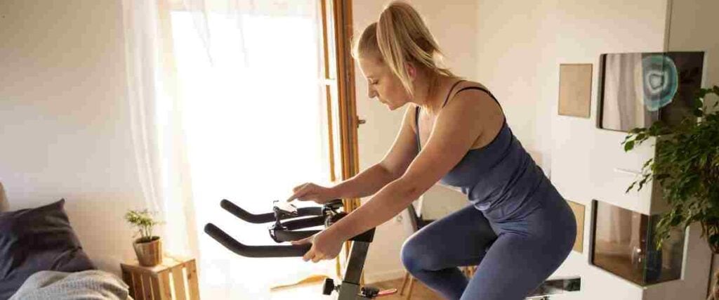 Woman on her indoor bike fixing her timer.