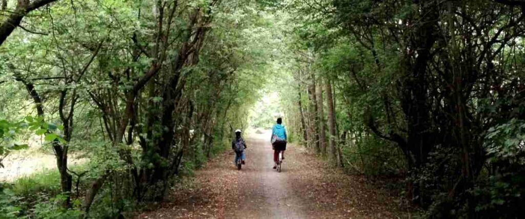 A mother and daughter biking on covered bike path. 