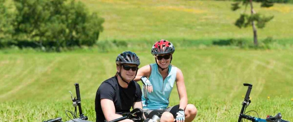 A couple cyclists in a field smiling. 