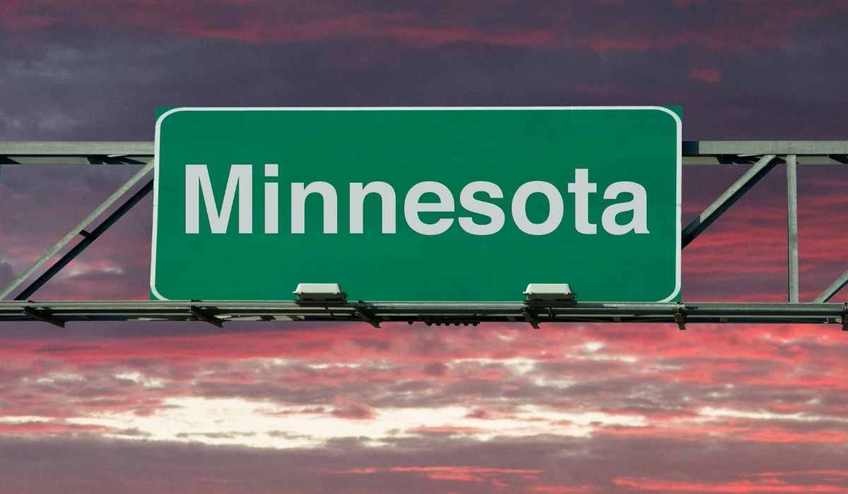 Minnesota state sign over highway during sun rise with bright orange and purple sky. 
