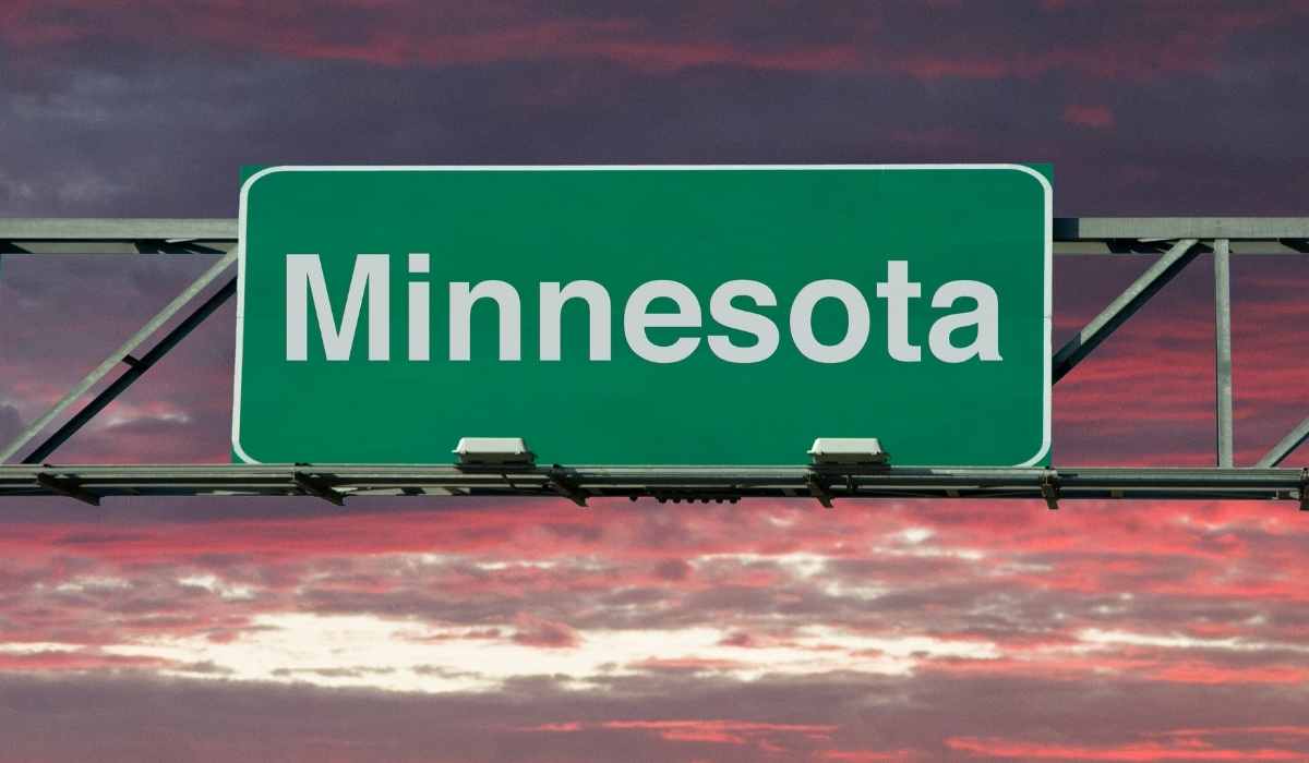 Minnesota state sign over highway during sun rise with bright orange and purple sky.