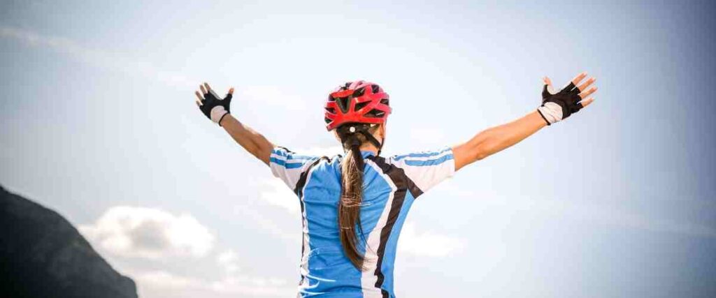 Female cyclist with arms stretched out towards the sky.
