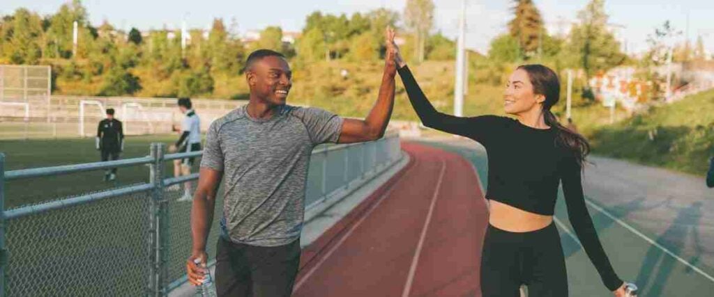 Man and women high fiving on running track. 