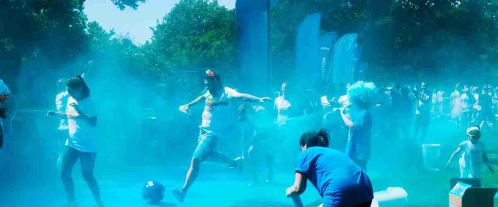 Group of runners at the end of color run being splashed with blue chalk. 
