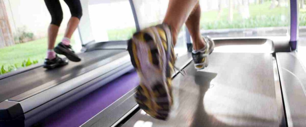 Close up of two set of feet running on a treadmill.