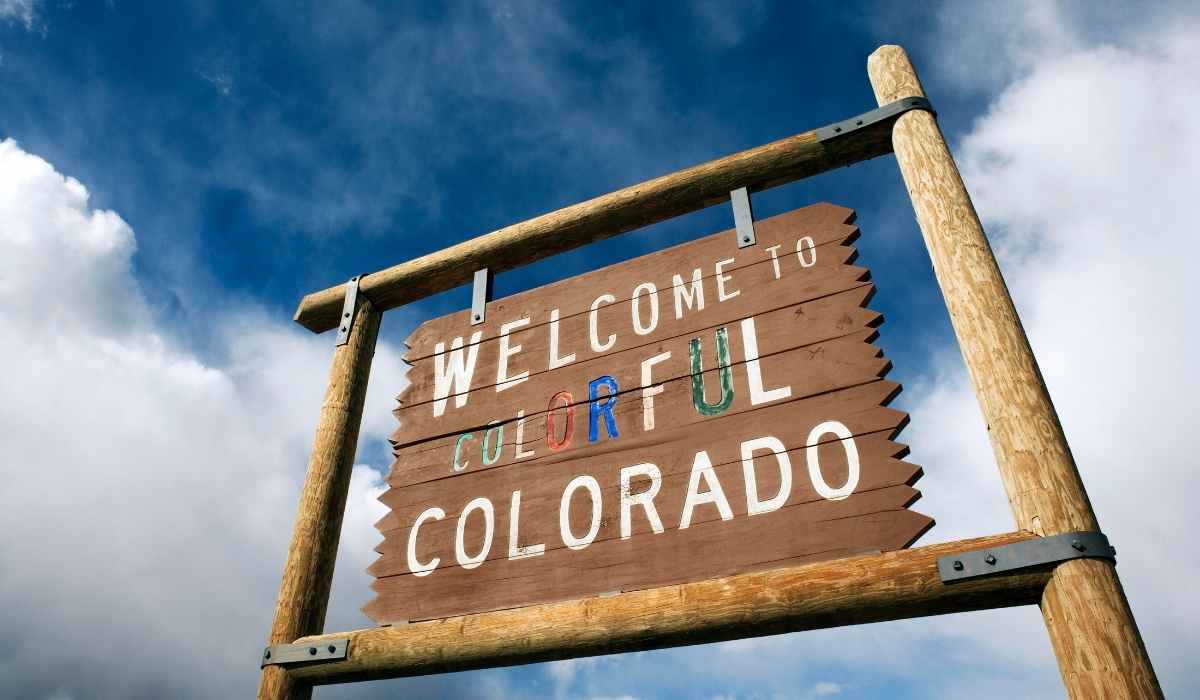 Big wooded 'Welcome to Colorful Colorado' street sign with the beautiful blue sky as its back drop. 