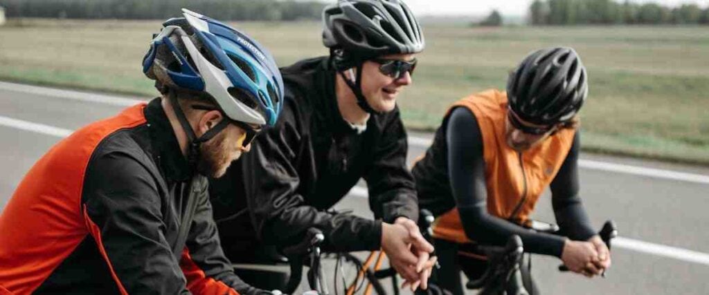 A group of male cyclists taking at the side of the road taking a break. 