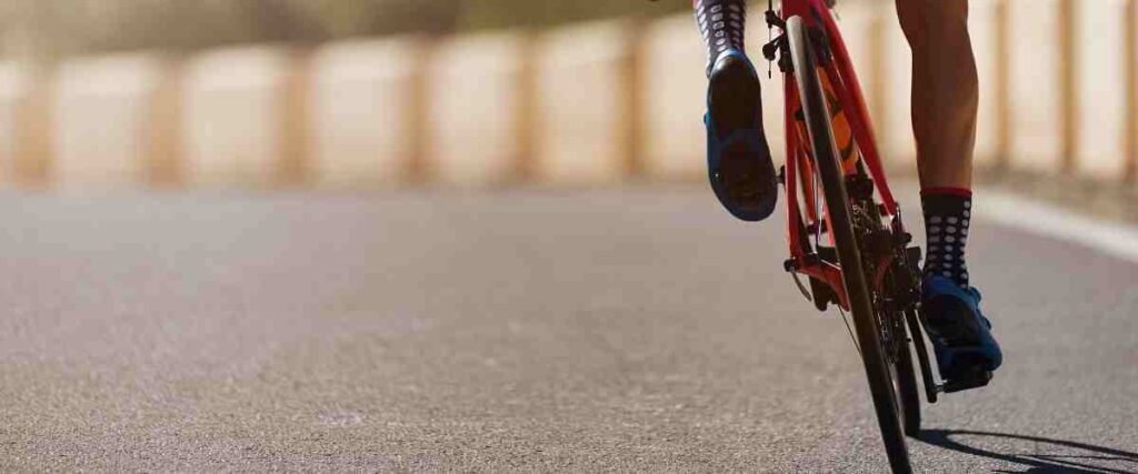 View of single cyclists and his back tire taking a turn on the bike track.