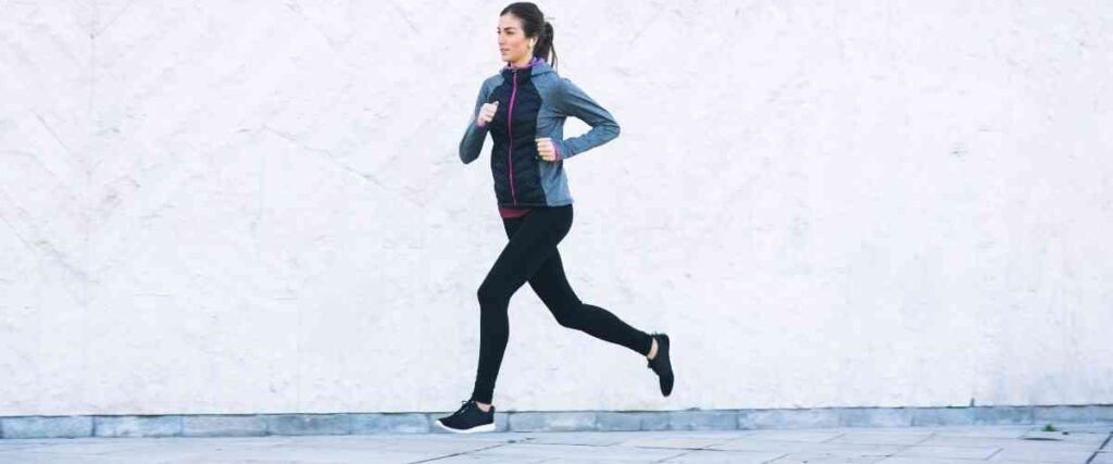 A woman running next to a white wall. 