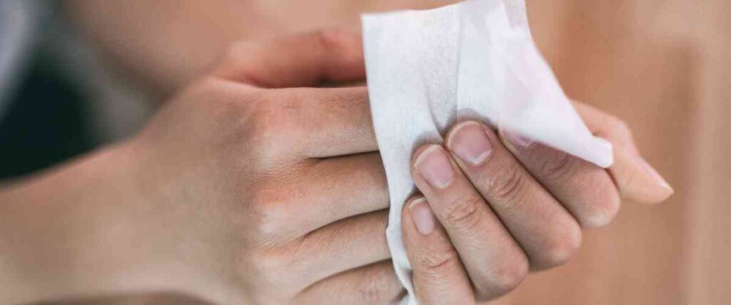 Woman wiping down her hands with paper towel.