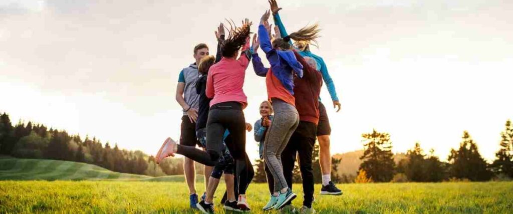Group of runners high-fiving mid-jump in a field. 