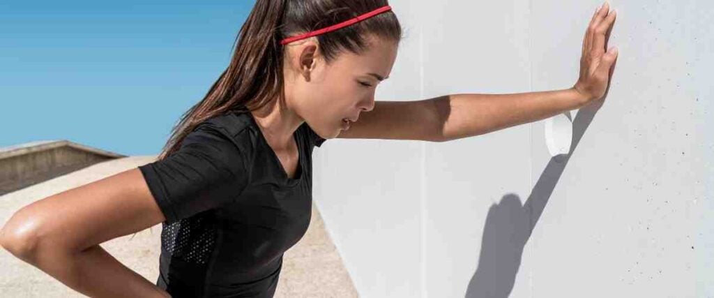 Woman sitting up against wall in running clothes. 