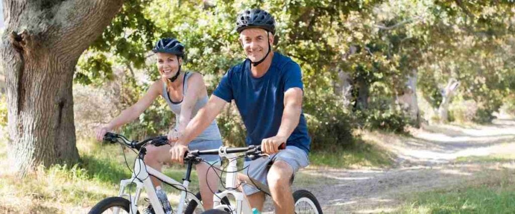 Older couple on bike path smiling at the camera. 