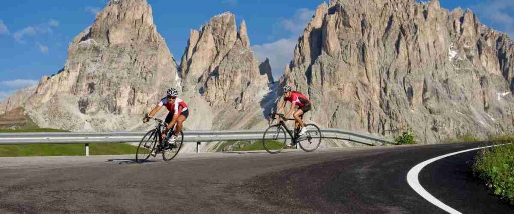 Two male cyclists coming around sharp turn on a mountain. 