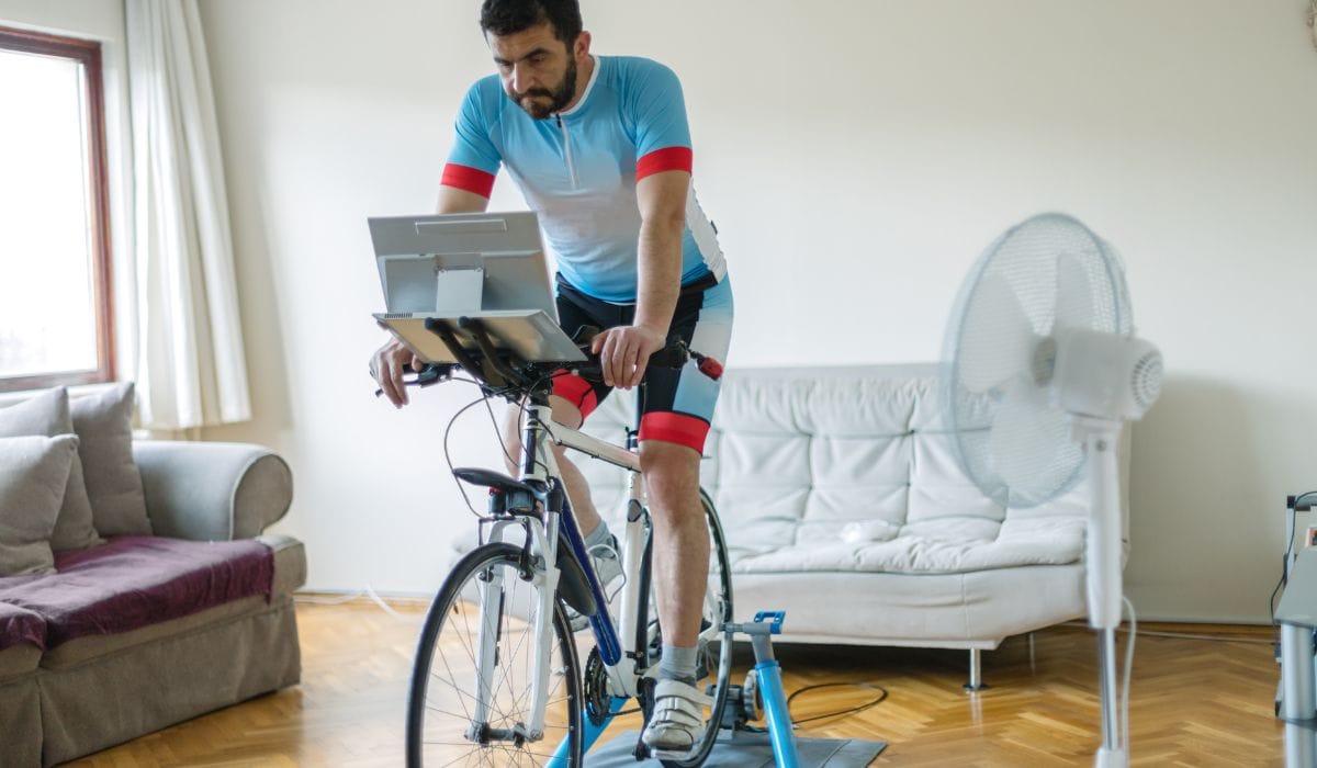 Man doing indoor cycling on a bike trainer with his computer attached to his bike. 