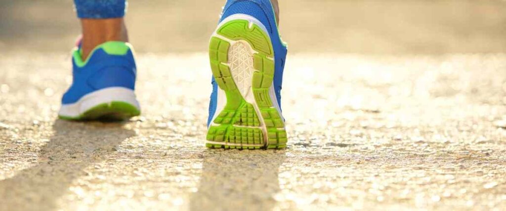Woman walking with back foot running shoe showing bottom.