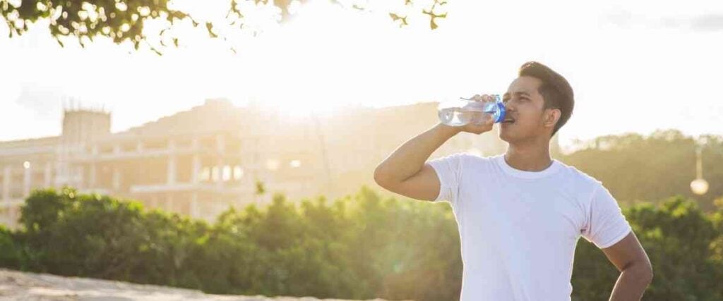 A man taking a drink of water about to start a run.