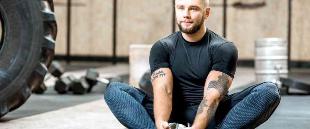 Man stretching in gym looking to the left.