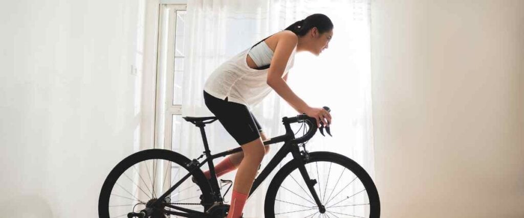 Woman riding a bike indoors look at the wall.
