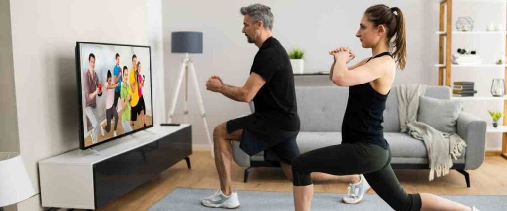 A couple doing a workout video in their living room. 