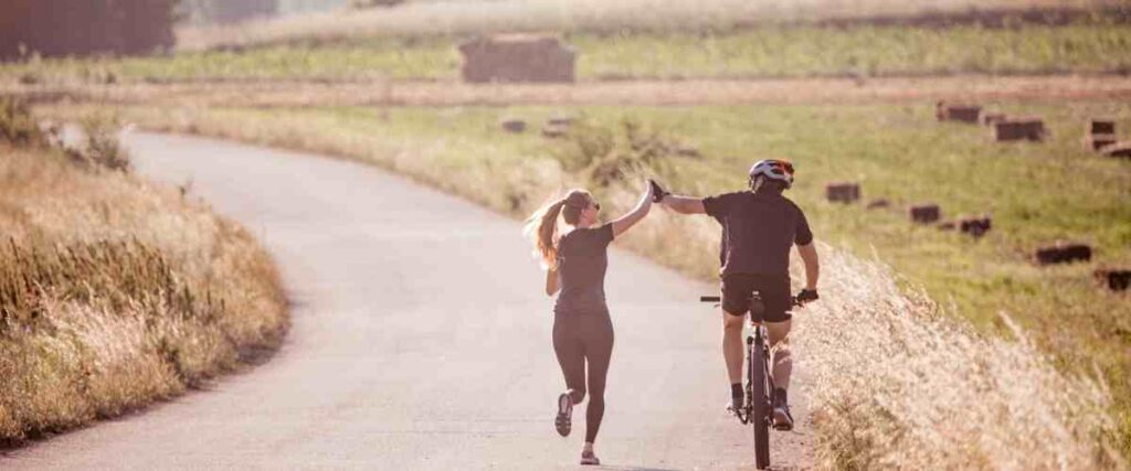 Couple high fiving while working out together outside.