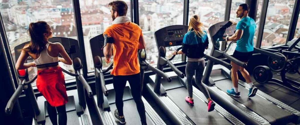 A group of people on a set of treadmills running or walking.