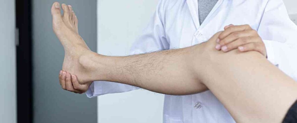 Doctor holding male patients leg.