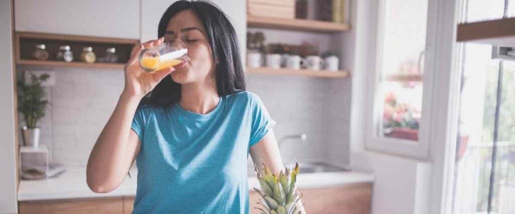 Woman drinking orange juice in her kitchen before starting her morning. 