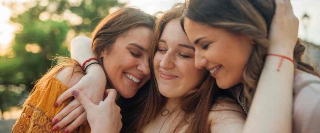 A group of female friends hugging and smiling clossly. 