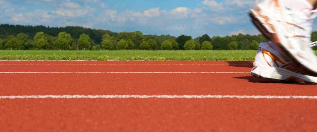 View of a runners shoes hitting a track and field before he takes off on his run.