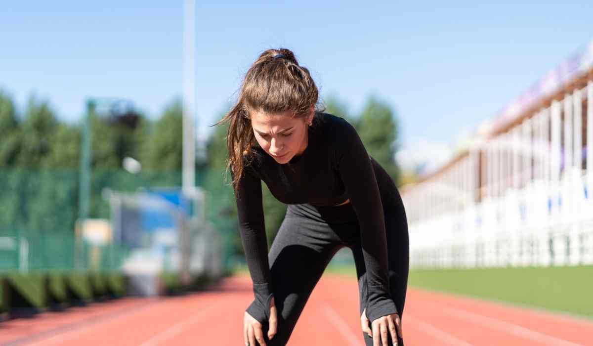 Woman hunched over after her run while on running school track.