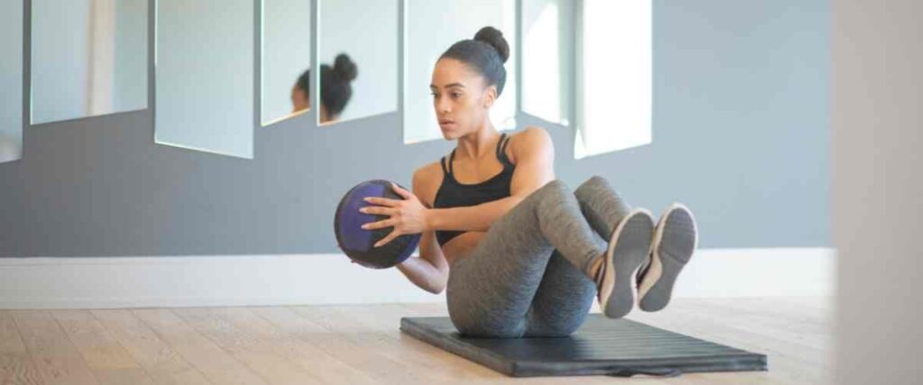 A woman doing crunches with a weighted ball in the early morning.
