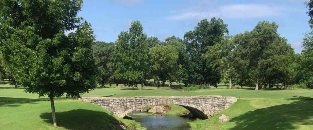 A park and a bridge over a small creek. 