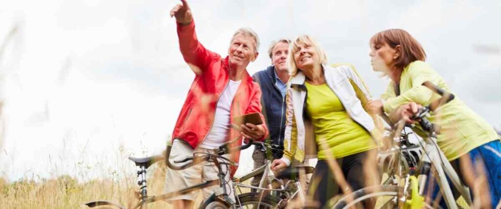 A group of people doing a biking tour stopping to look at something the tour guide is pointing out.