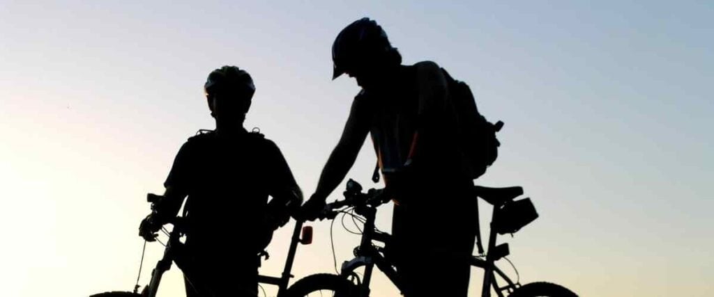 Two cyclists silhouettes stopping with the sun coming up. 