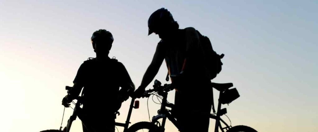 Two cyclists silhouettes stopping with the sun coming up.