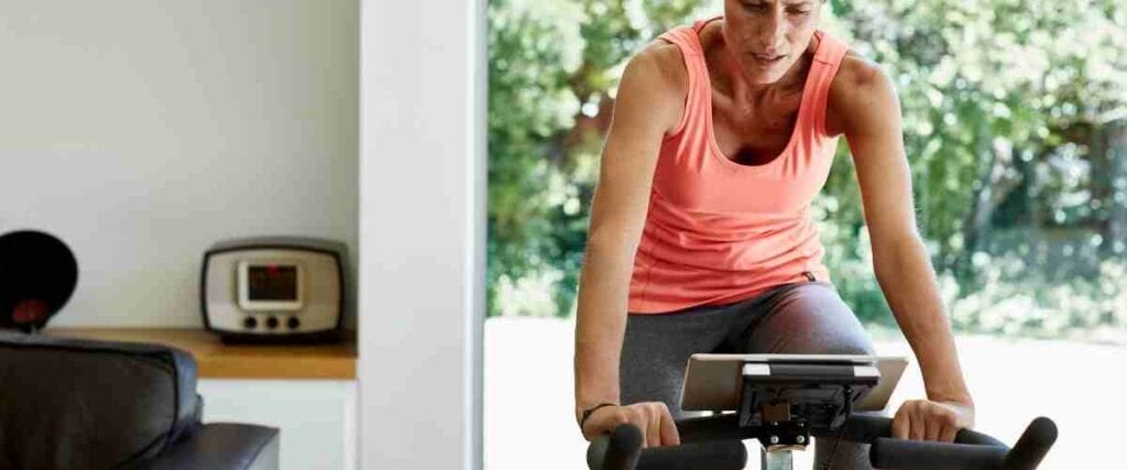 A woman on her indoor exercise bike doing a workout in her living room.