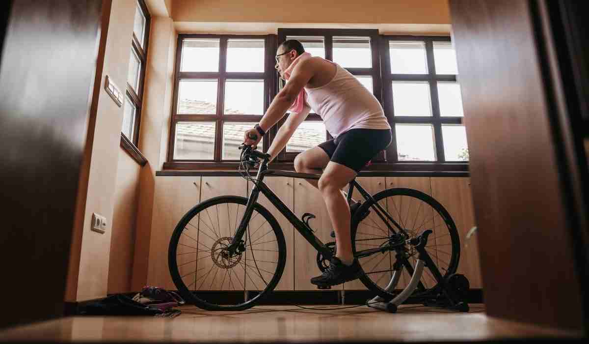 Male cyclists on his indoor trainer next to his windows in his living room. 